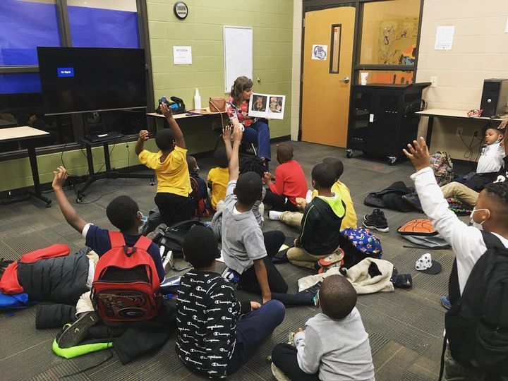 Group of kids listening to Ms. Kristin reading a story at Boys & Girls Club