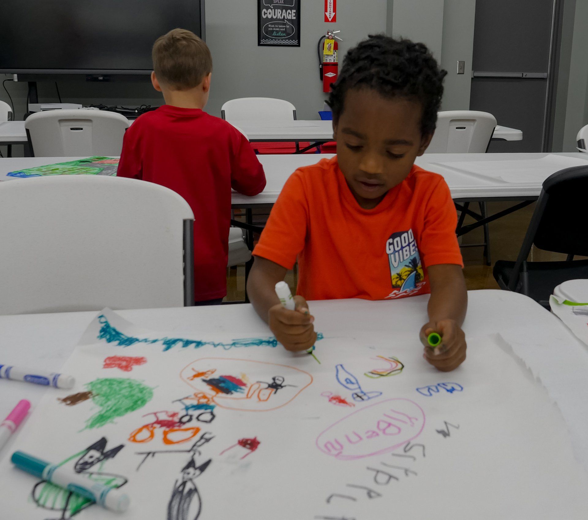 Two boys drawing at a classroom table during Boys & Girls Club art activity