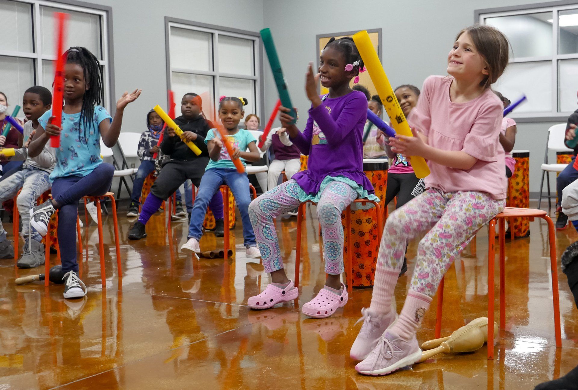 Kids raising instruments and clapping during music activity at Boys & Girls Club