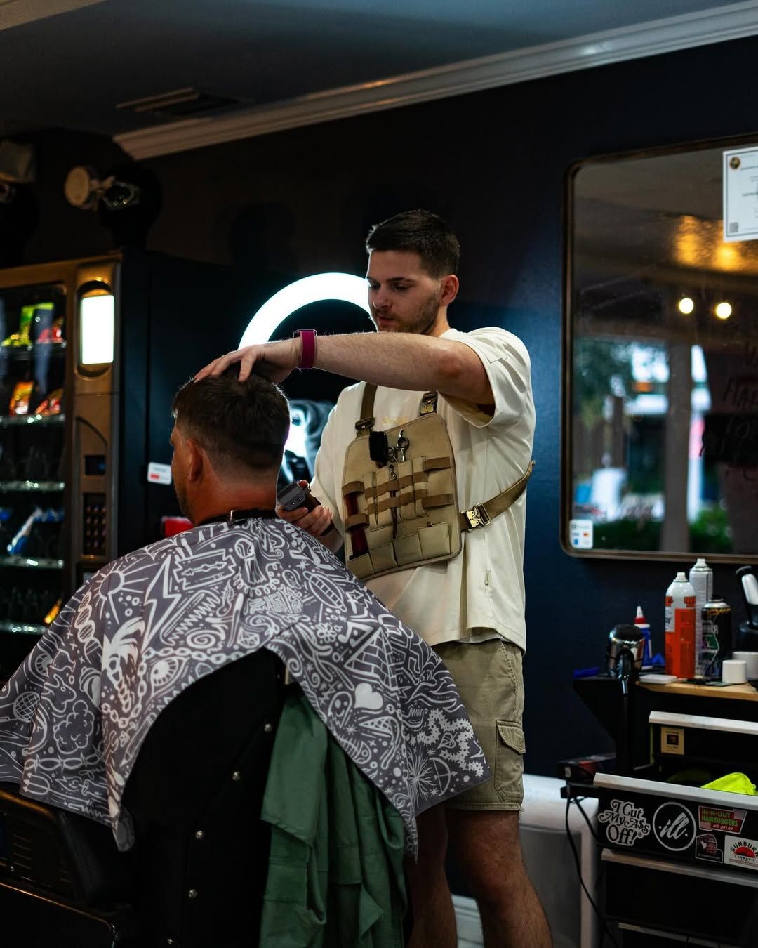 Man getting a haircut by a barber wearing a tool vest
