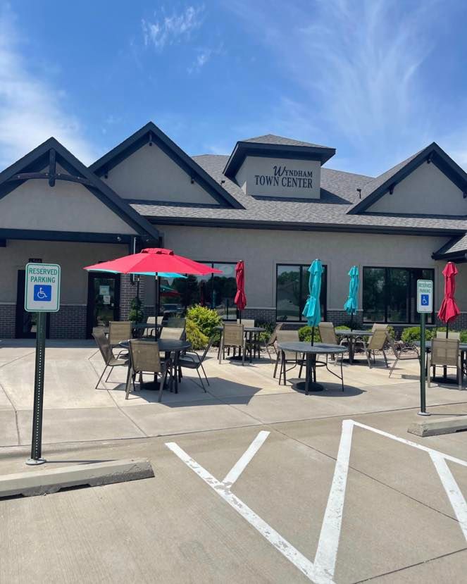 Restaurant exterior with patio seating under colorful umbrellas. Accessible parking sign is visible.