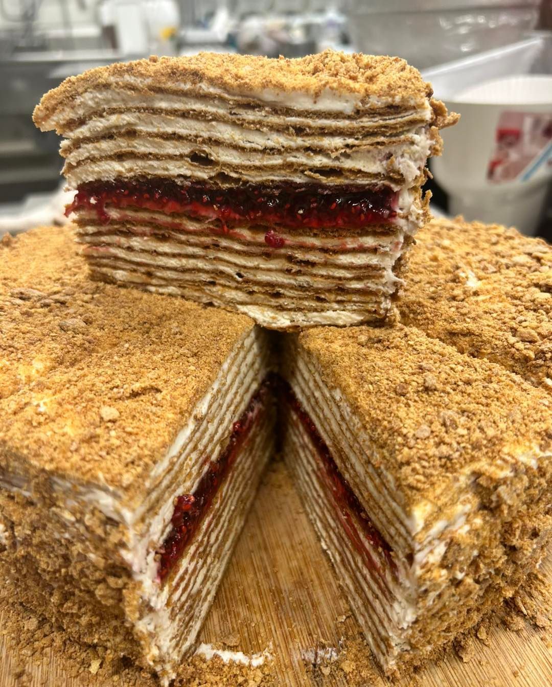 Layered cake with raspberry filling, covered in crumbs, sliced.