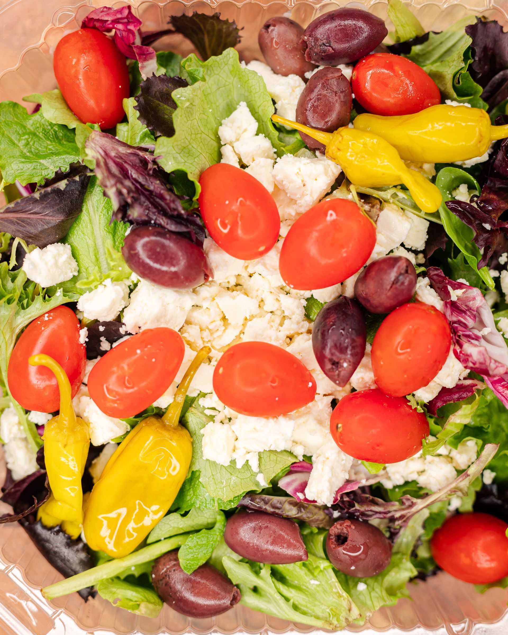 Salad with tomatoes, olives, feta cheese, and pepperoncini.