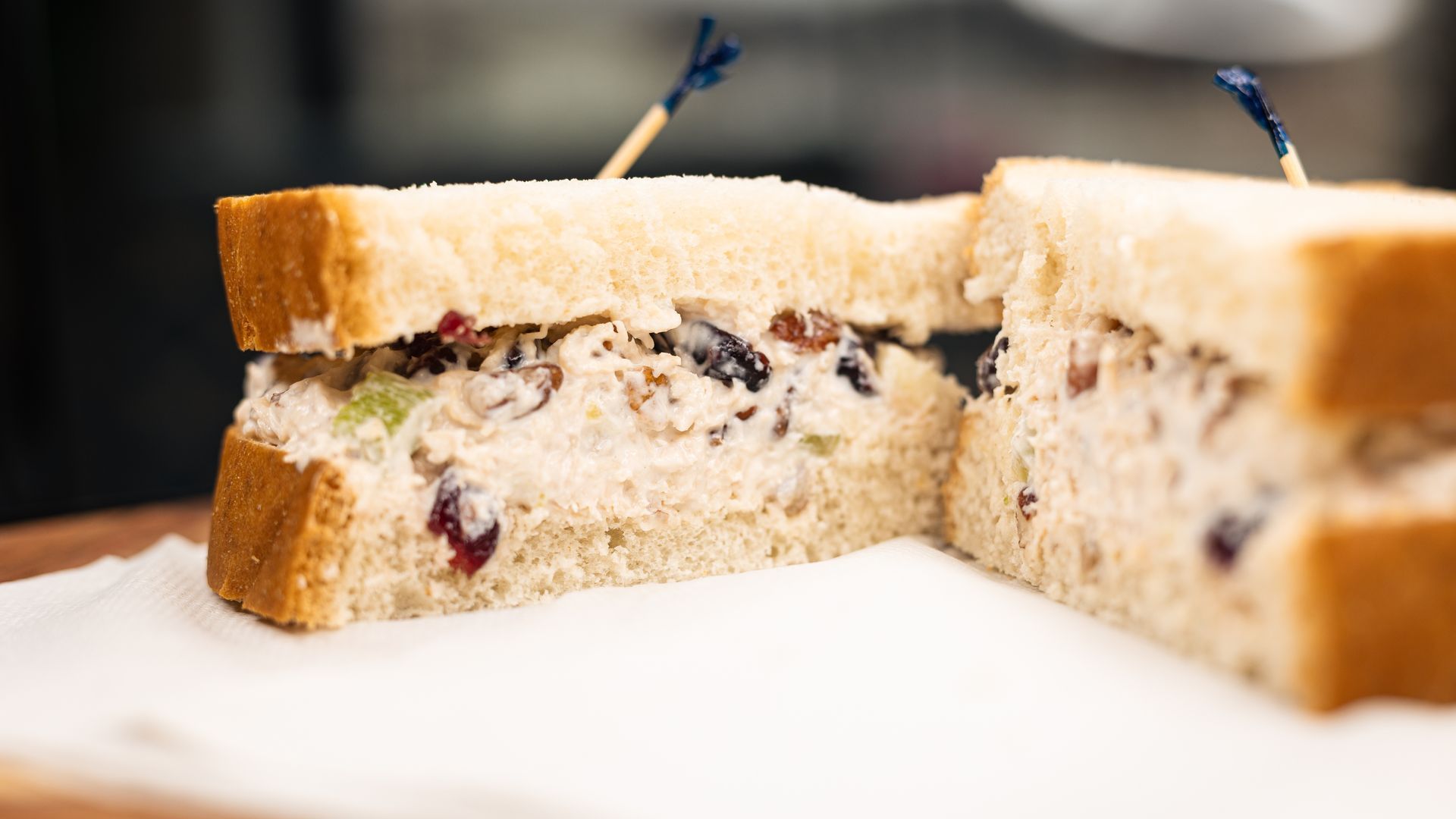 Chicken salad sandwich, cut in half, on white bread. Garnished with toothpicks.