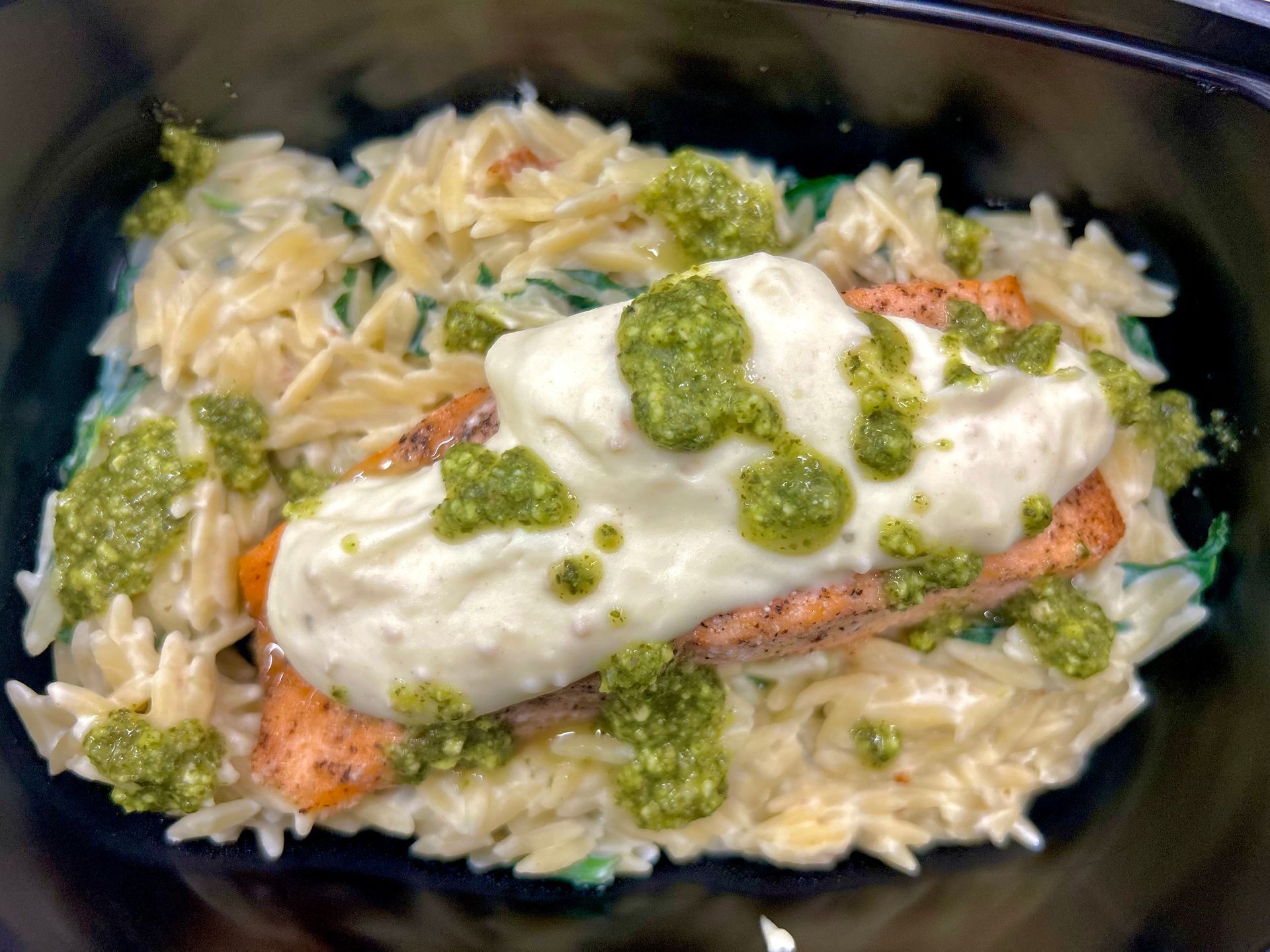 Salmon with pesto and creamy sauce over orzo pasta.