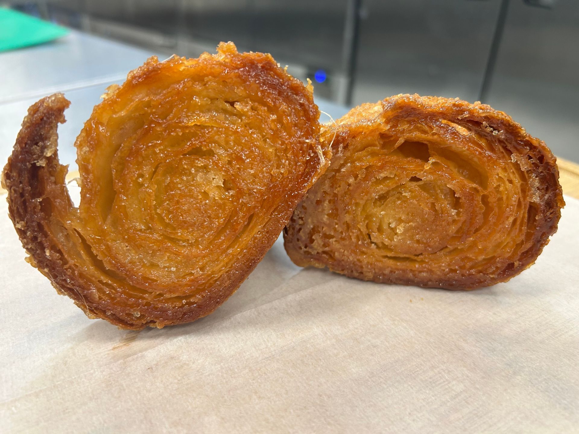 Two halves of a pastry, with layered, spiral texture, coated in sugar.