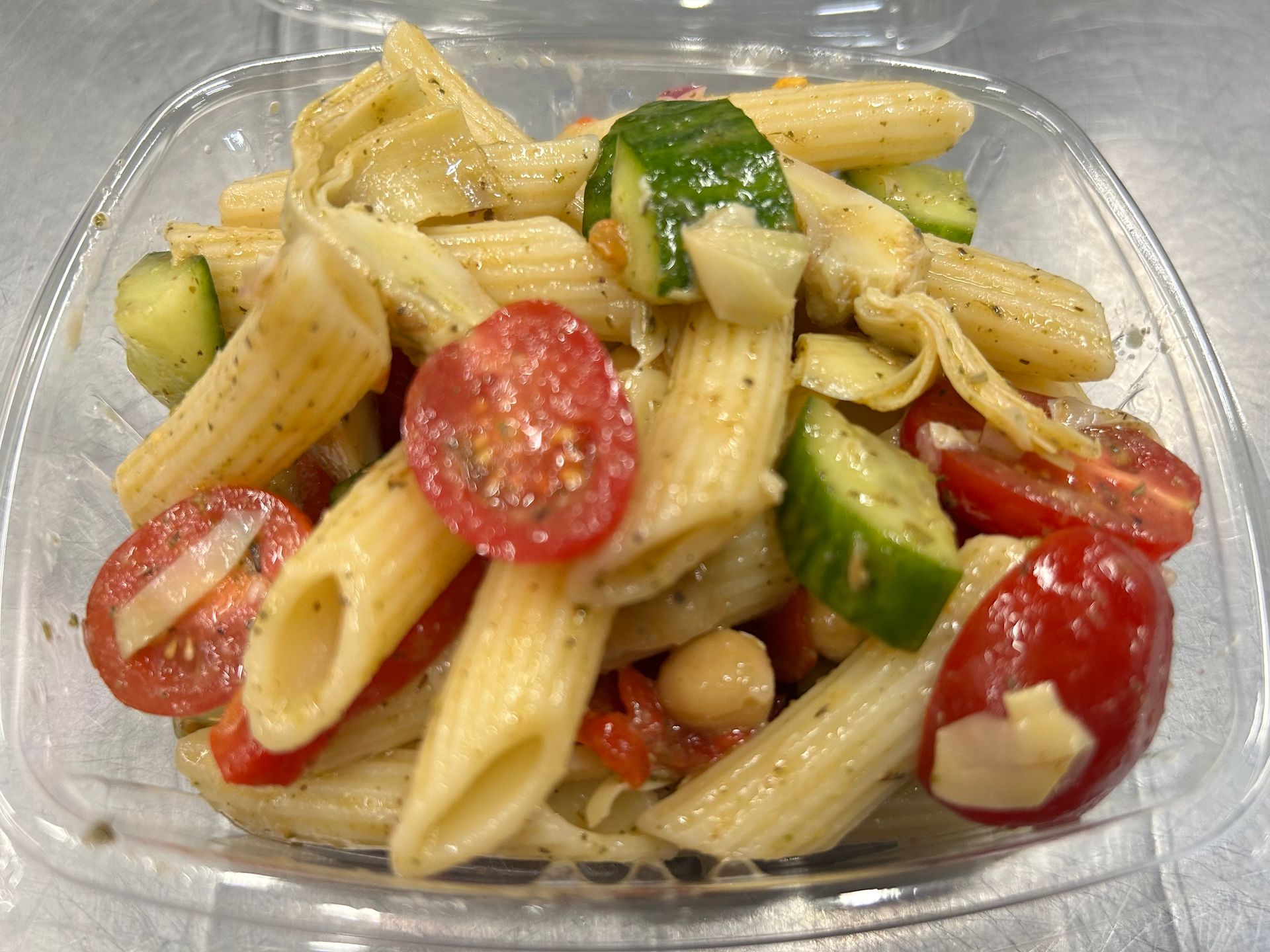 Pasta salad with penne, tomatoes, cucumber, and artichoke hearts.
