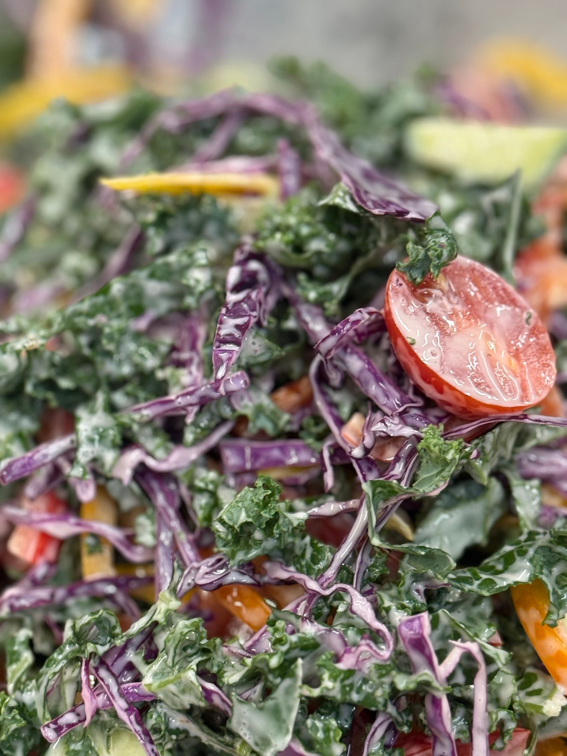 Kale and red cabbage salad with tomatoes, coated in creamy dressing.