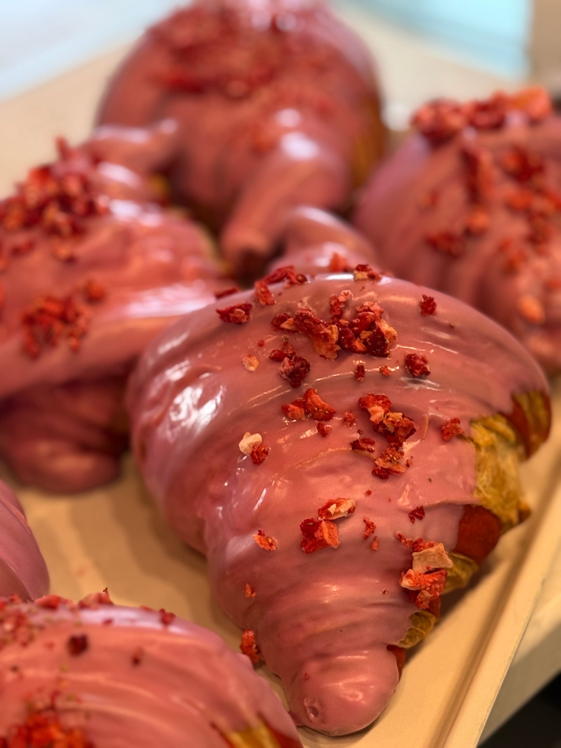 Pink-glazed croissants with strawberry crumble, close-up shot.