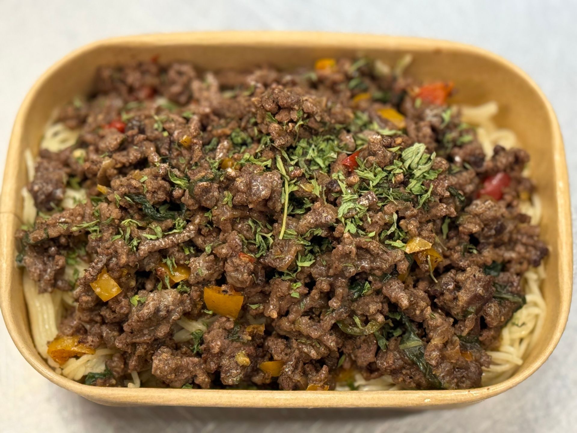 Pasta dish with ground meat, yellow and red peppers, and herbs.
