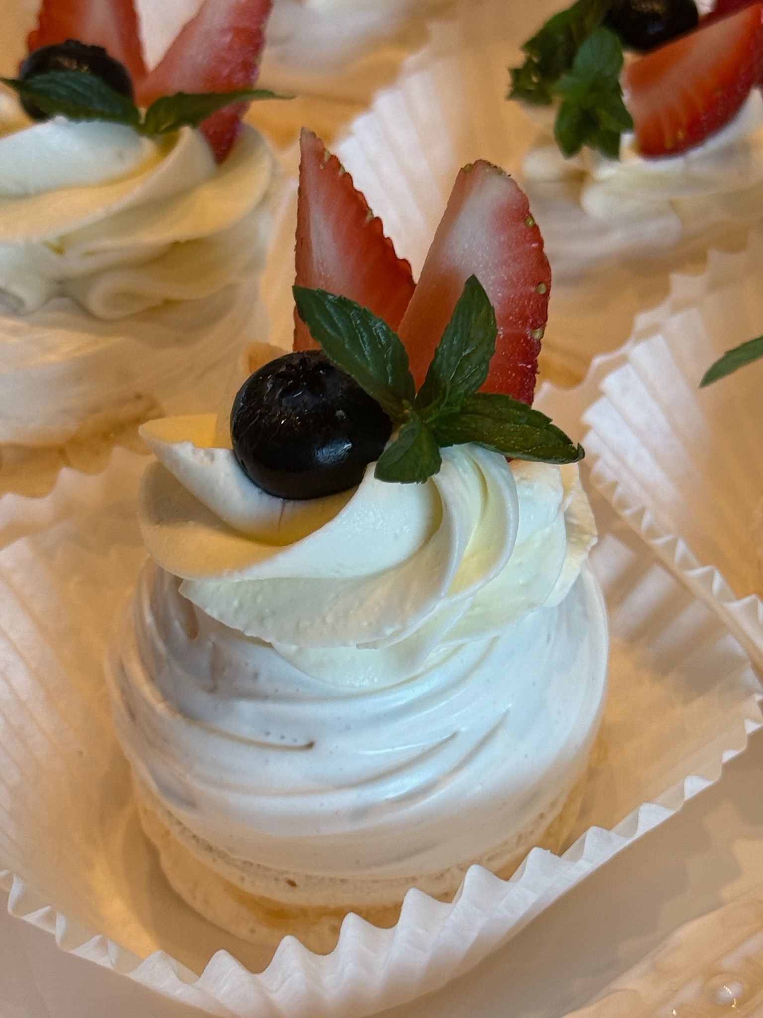 Mini pavlova dessert with whipped cream, strawberries, blueberries, and mint leaves.