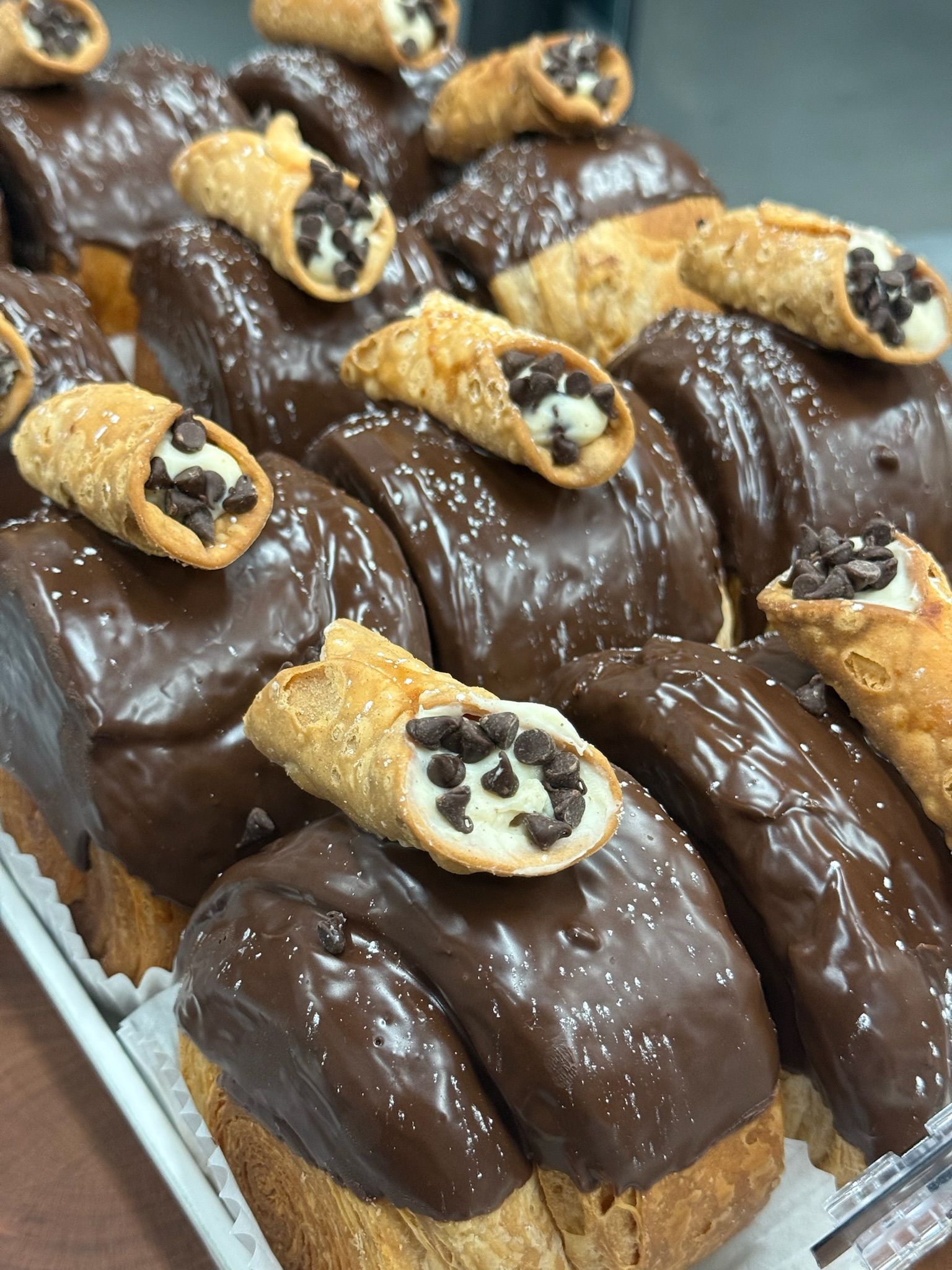 Chocolate frosted pastries with mini cannolis, sprinkled with white dots.