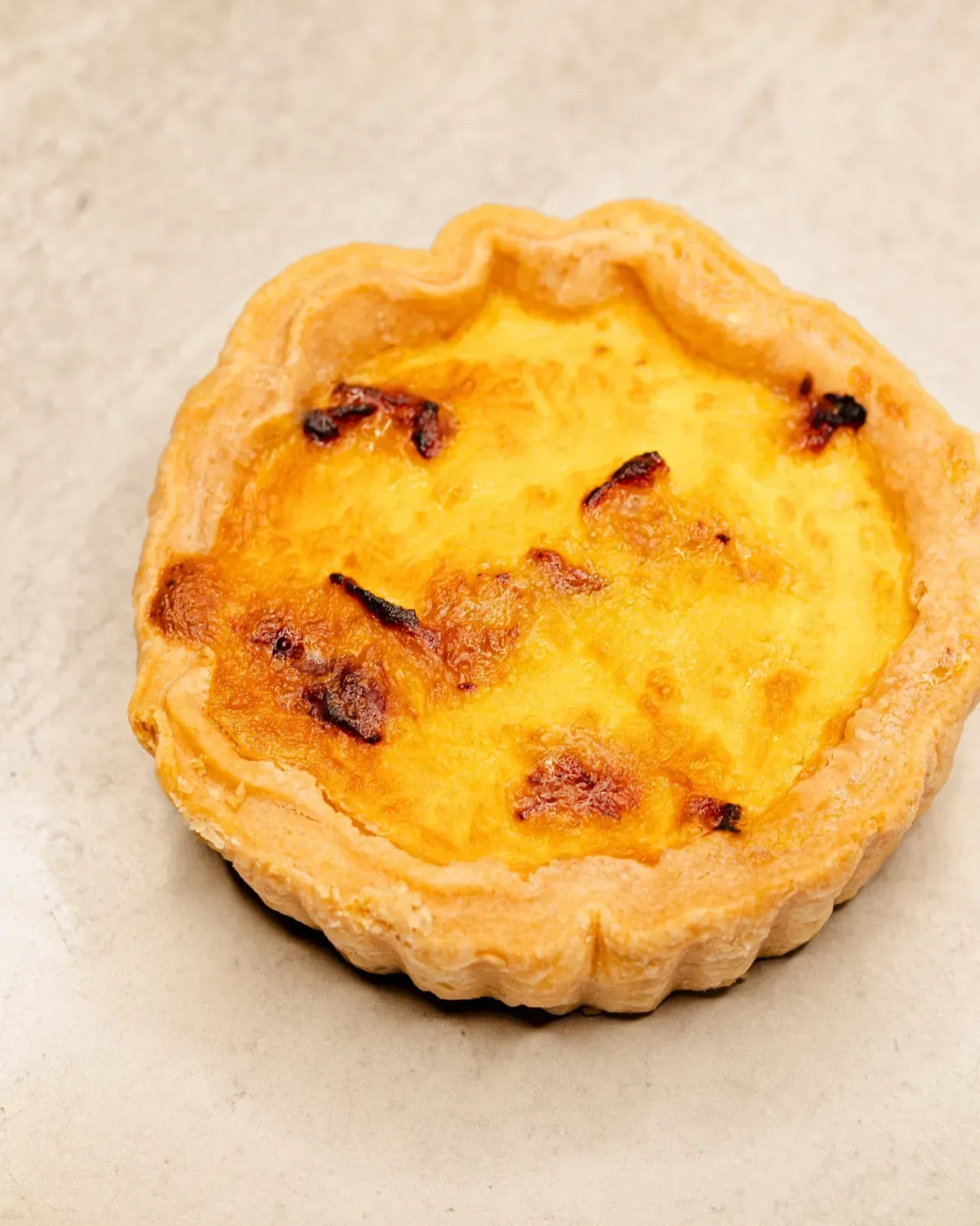 Small quiche with golden custard filling and a flaky crust.