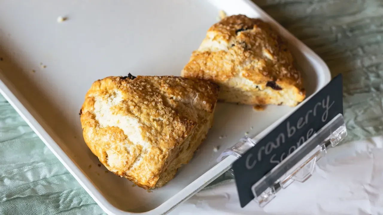 Two cranberry scones on a white tray, with a handwritten 