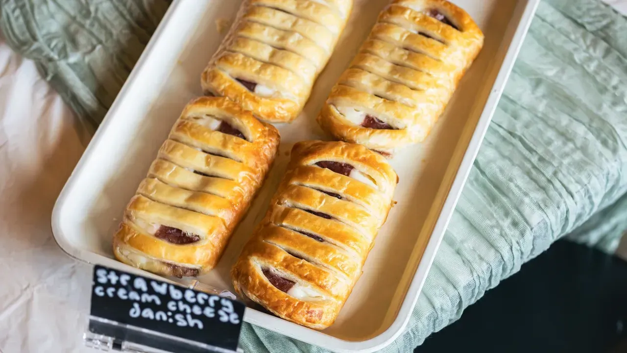 Four strawberry cream cheese danishes in a white tray.