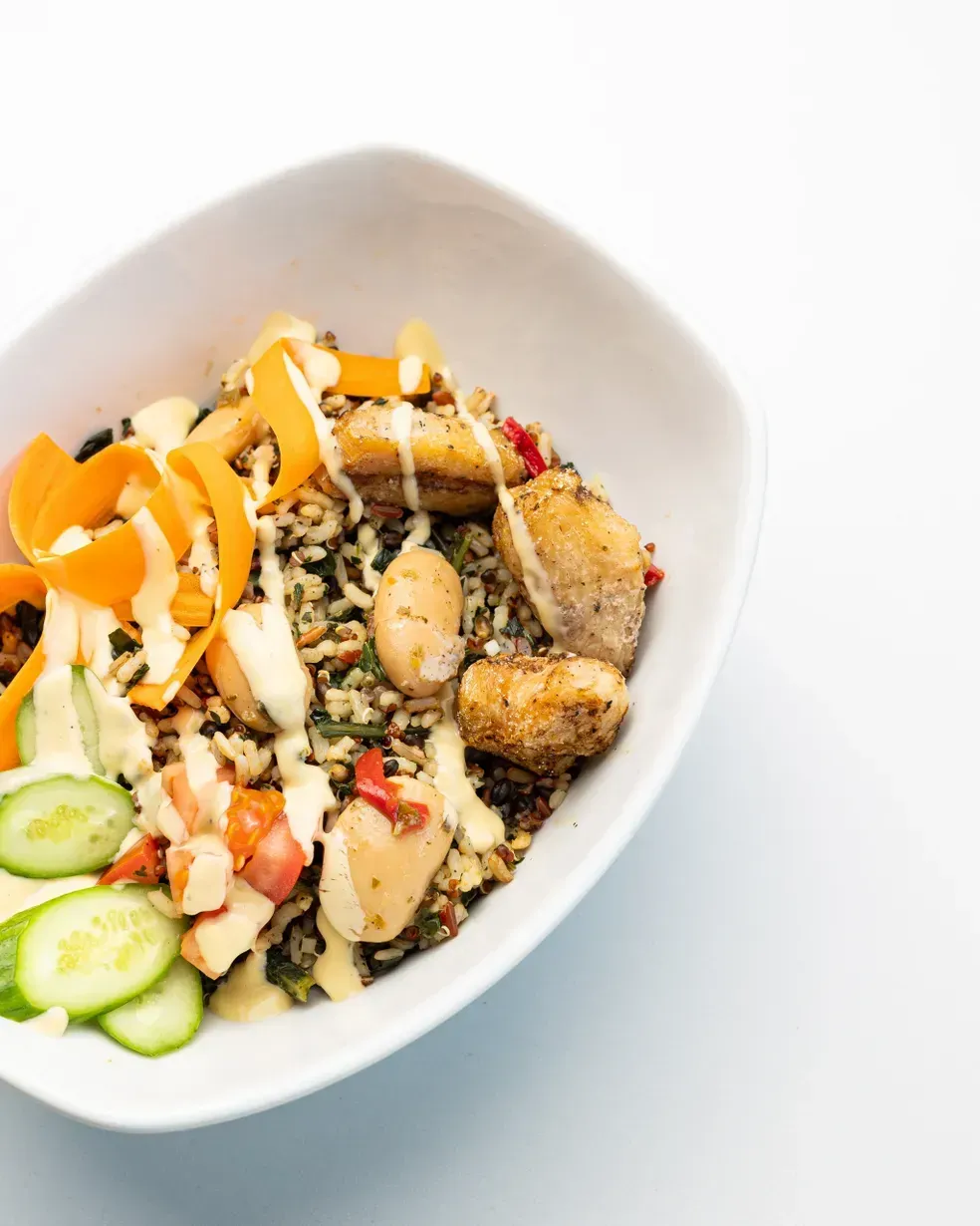 Bowl of food: rice, beans, fish, vegetables, and sauce.