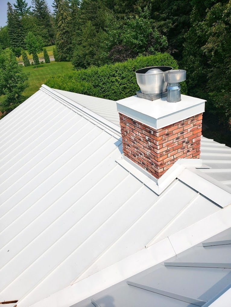 A white roof with a brick chimney on top of it.