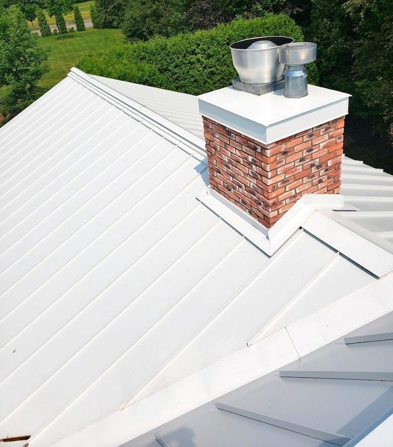 A white roof with a brick chimney on top of it