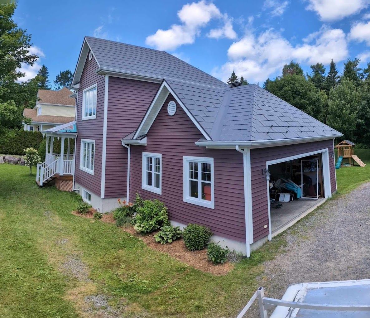 A large purple house with a gray roof and a garage.