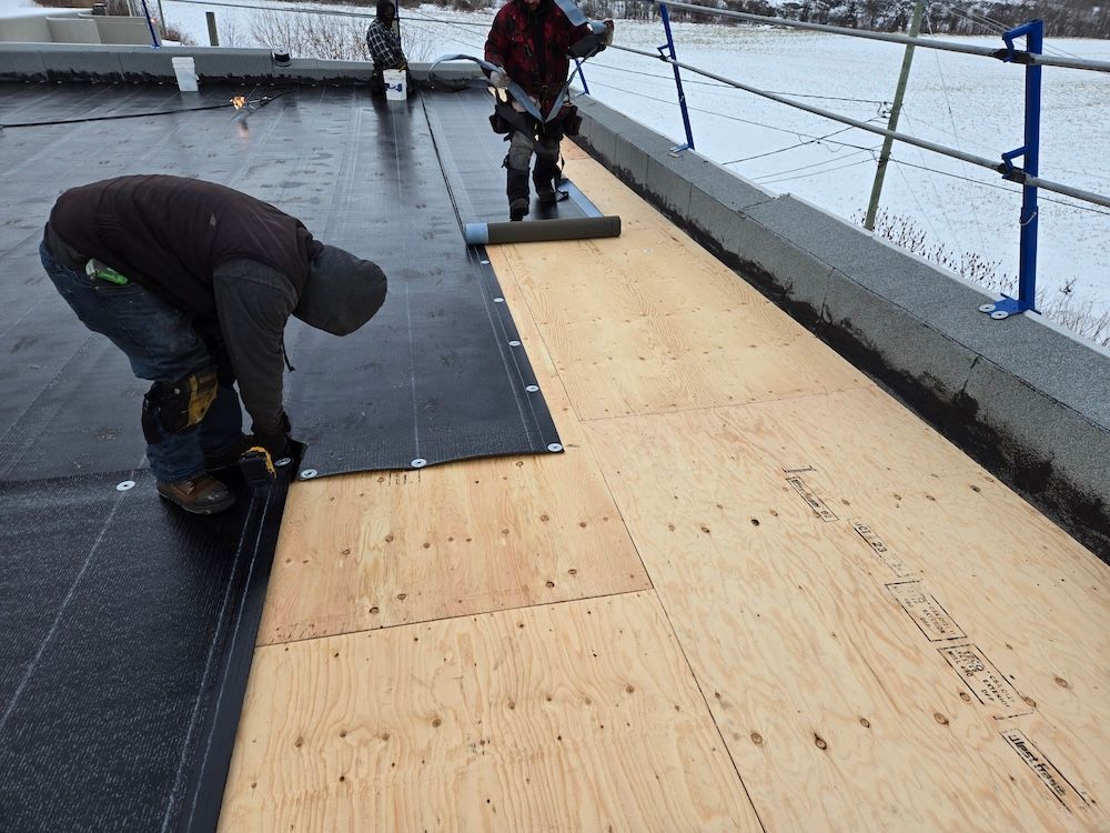 Two men are working on a roof in the snow.