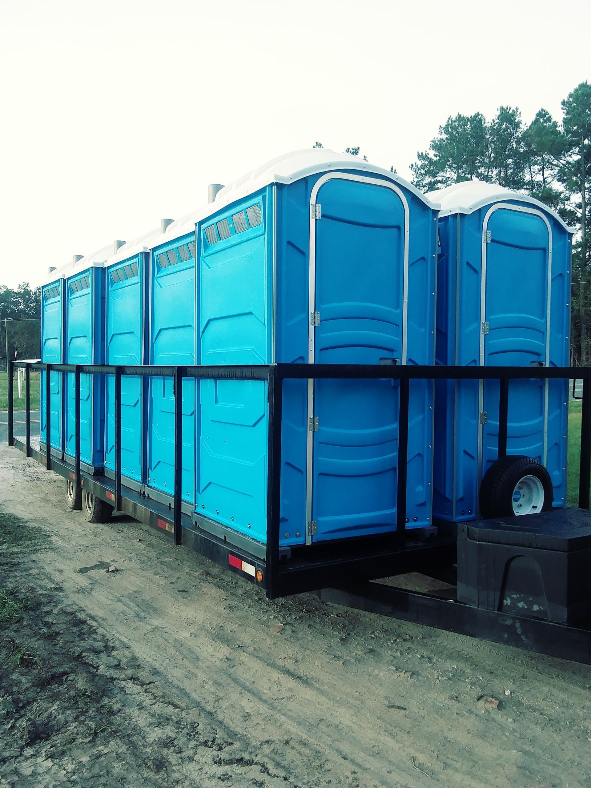 A row of blue portable toilets are sitting on top of a trailer.