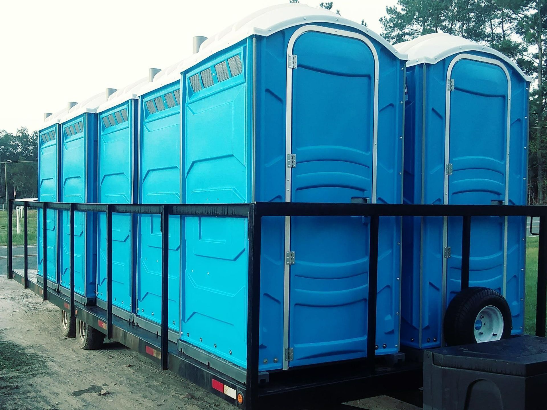 A row of blue portable toilets on a trailer