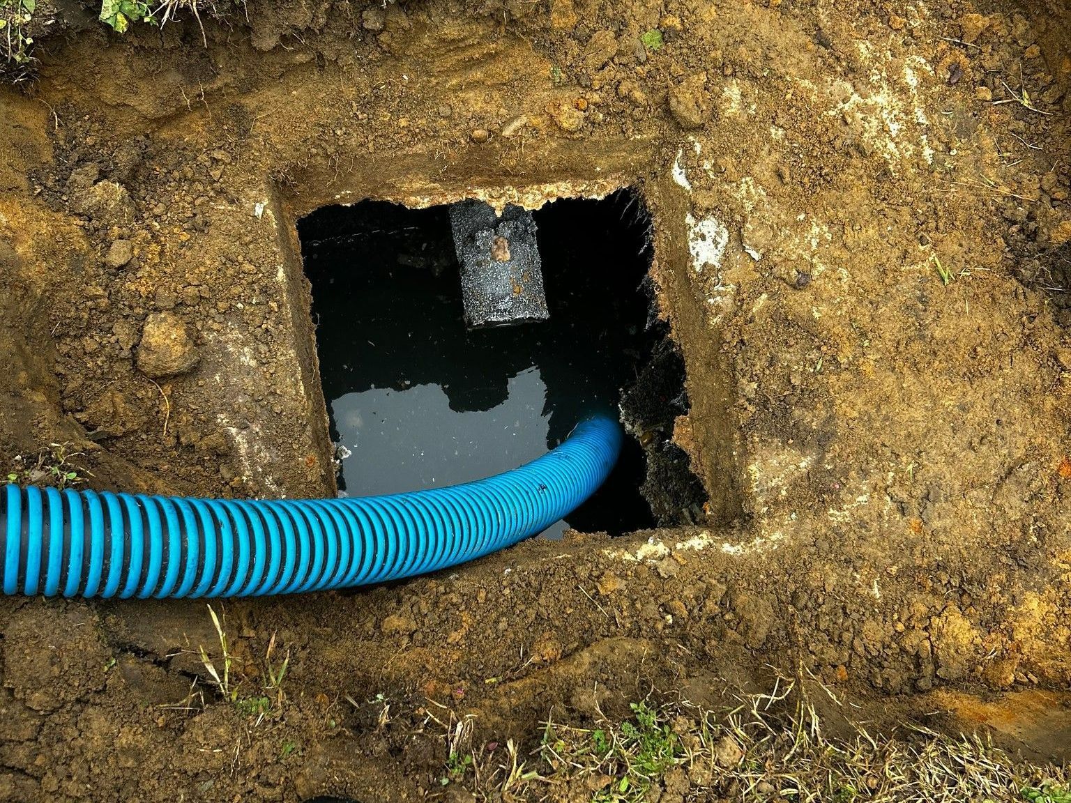 A blue hose is connected to a hole in the ground.