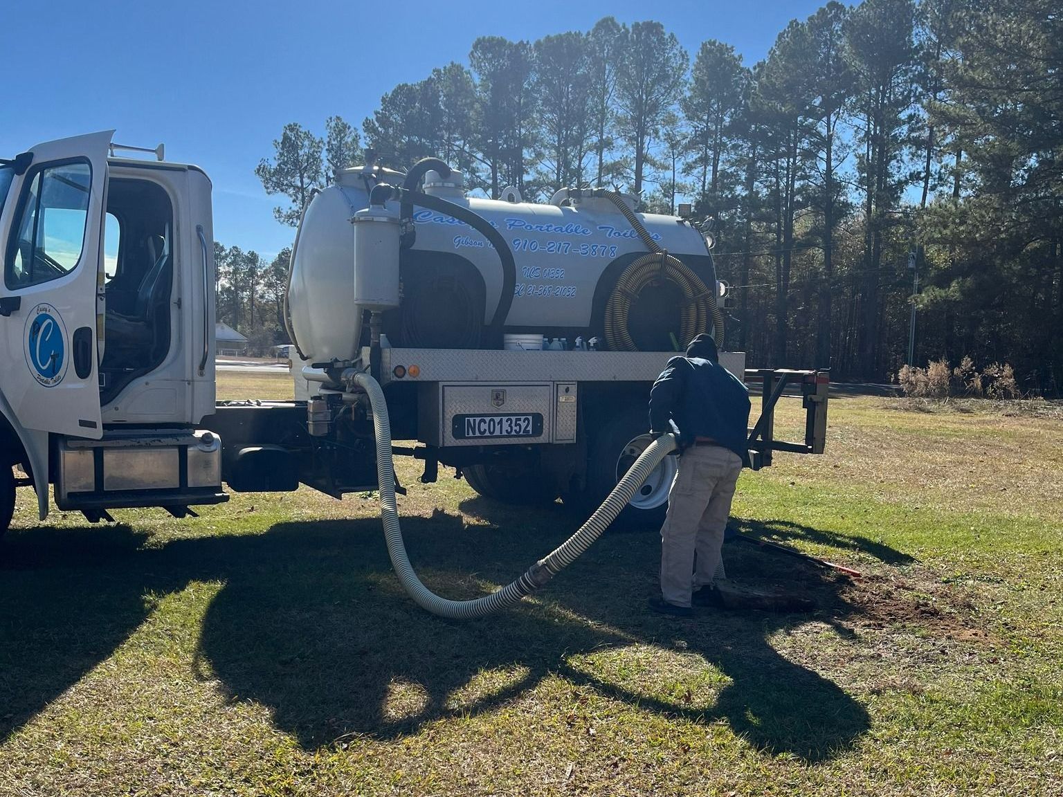 A man is standing in front of a vacuum truck that says e. smith on the back