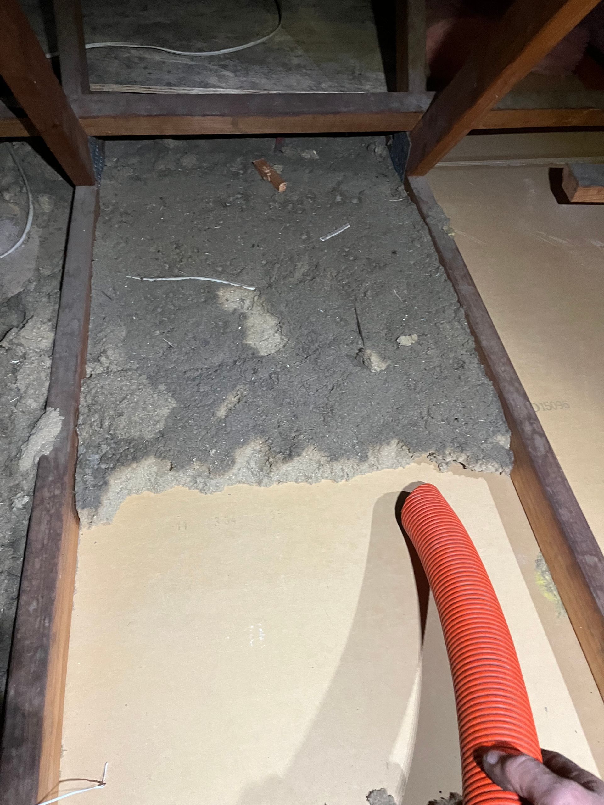 Close up picture of old insulation being vacuumed from roof cavity.