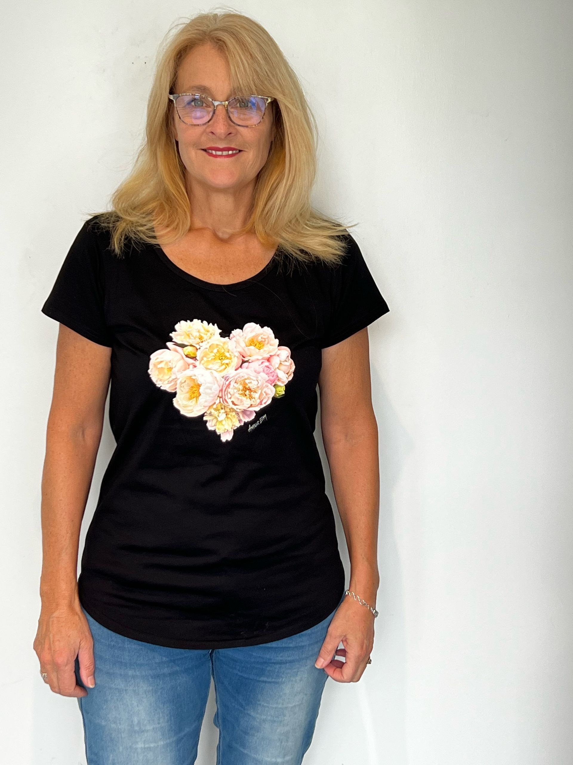A woman wearing a black shirt with a heart of flowers on it