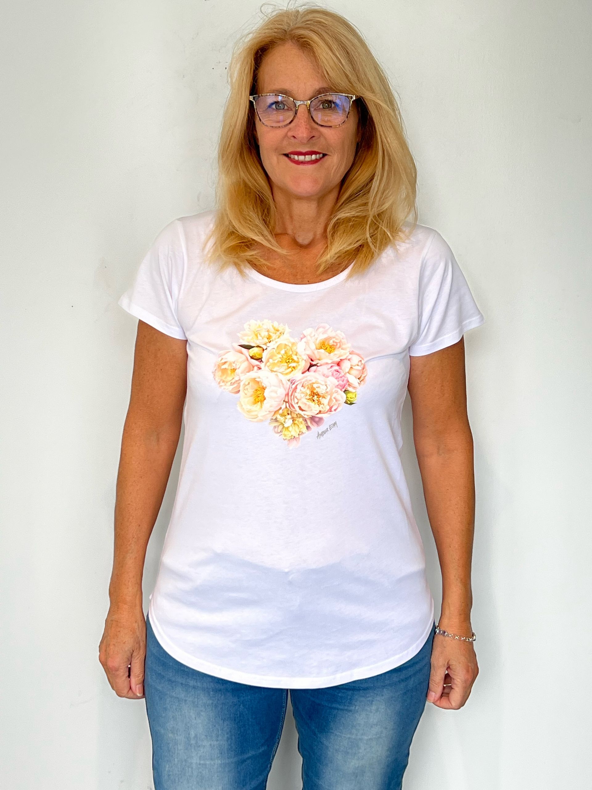 A woman wearing glasses and a white t-shirt with flowers on it.