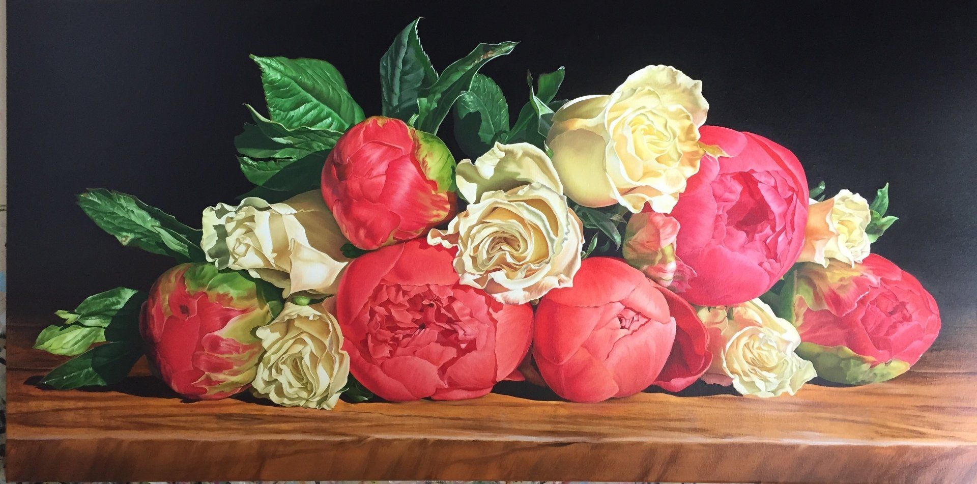 A painting of red and white flowers on a wooden table