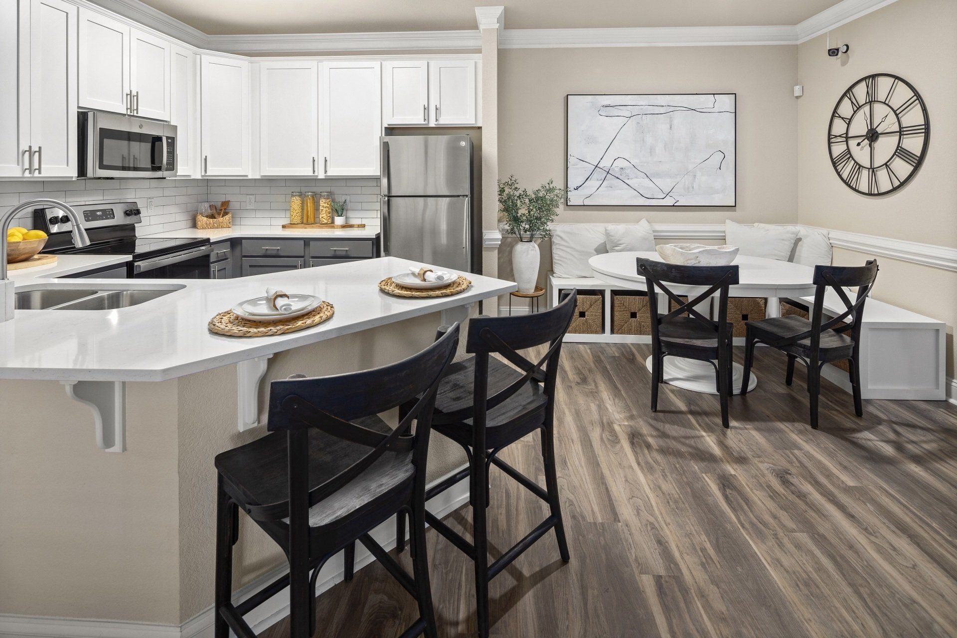Kitchen with white cabinets, island, stainless steel appliances, and a dining nook with chairs.