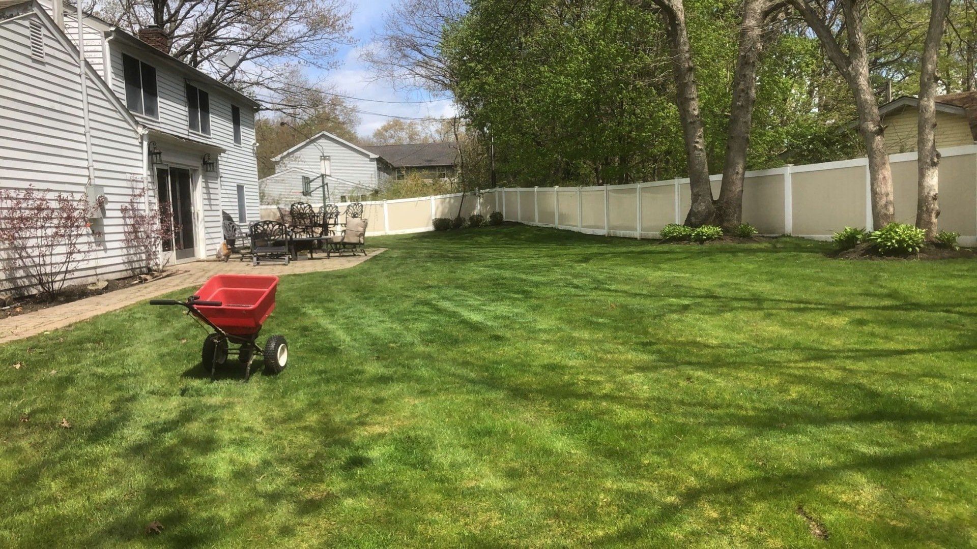 A red wheelbarrow is sitting in the middle of a lush green lawn.