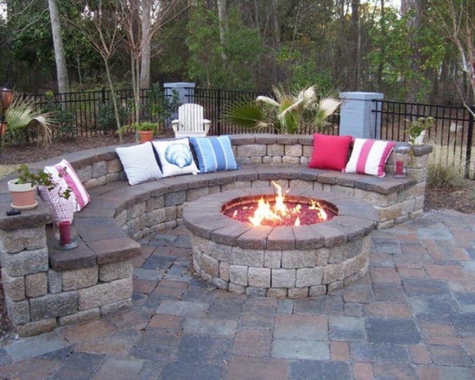 A fire pit is surrounded by a bench and pillows