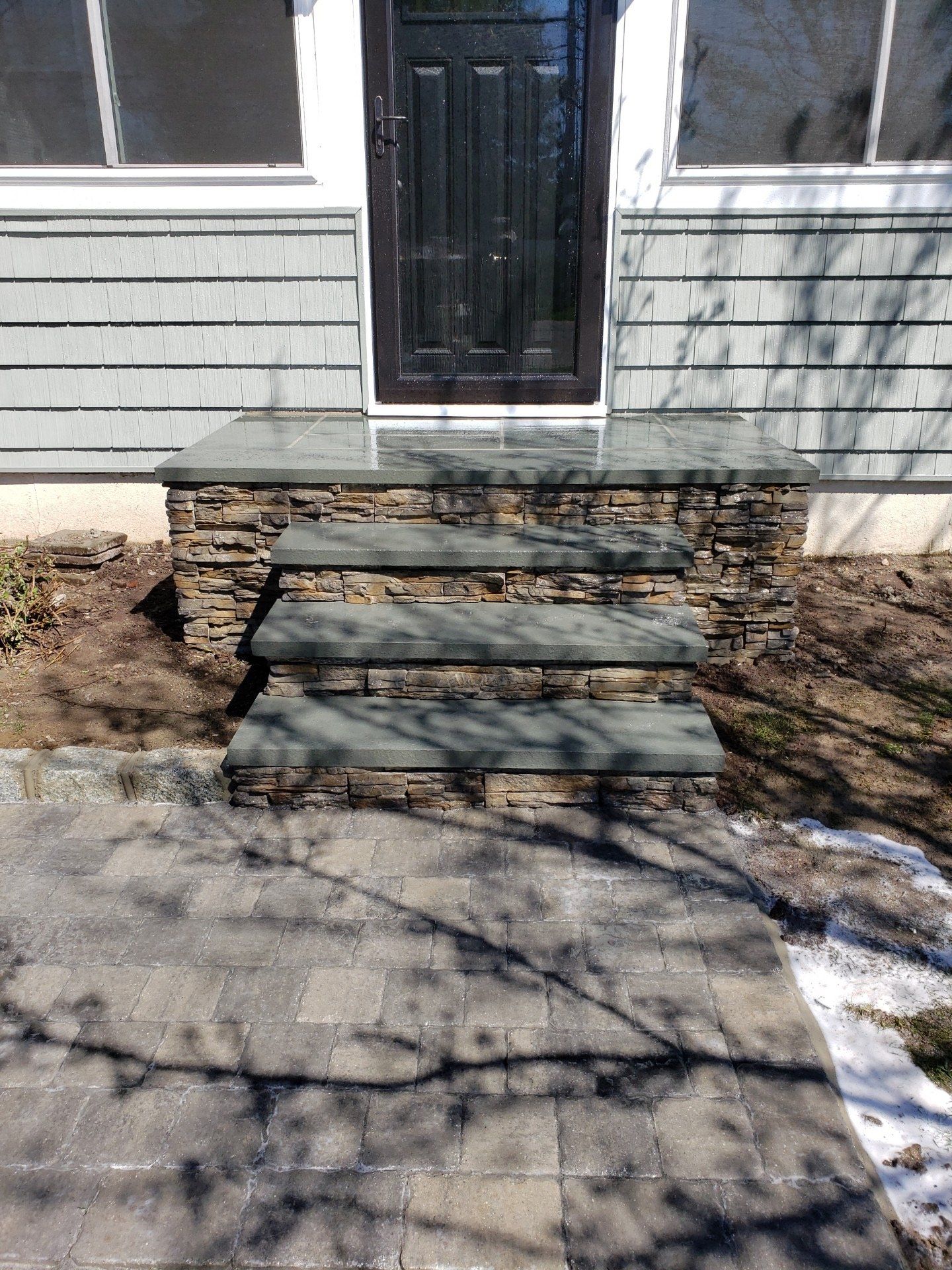 A stone porch with steps leading to the front door of a house.
