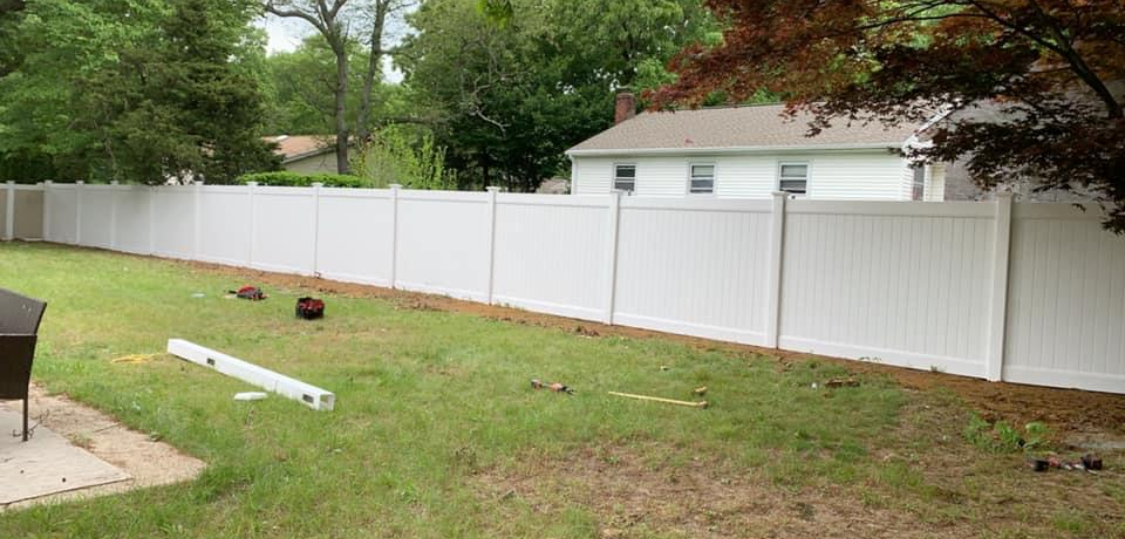 There is a white fence in the backyard of a house.