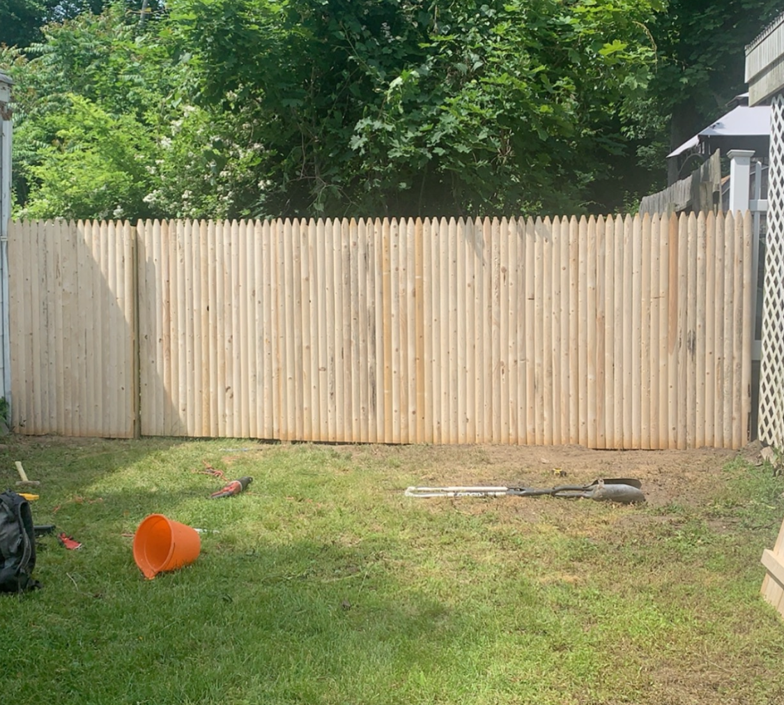 A wooden fence is sitting in the middle of a lush green yard.