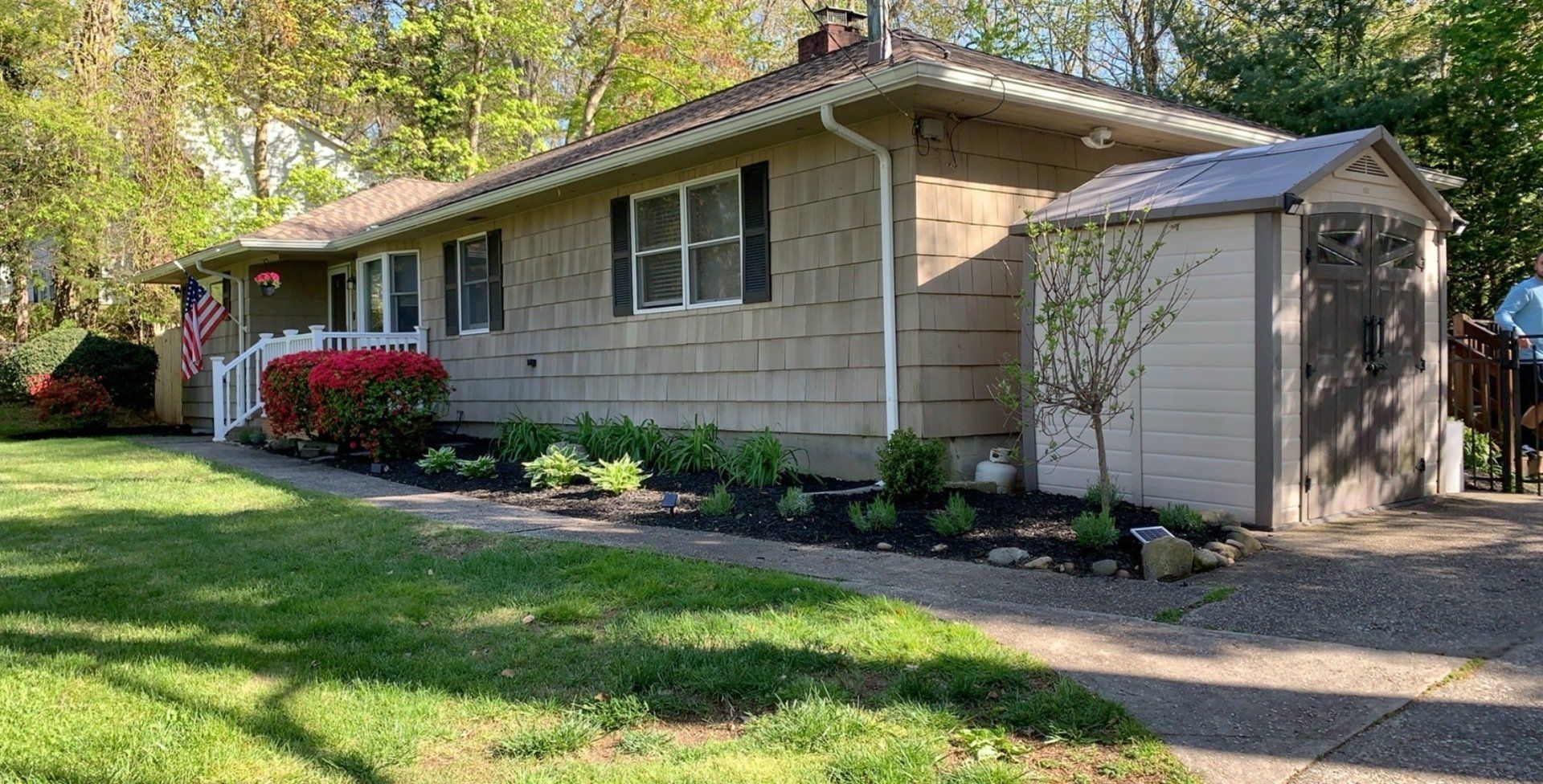A house with a shed in front of it and a lush green yard.