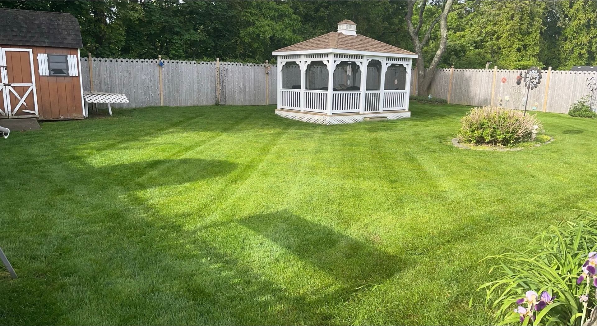 A gazebo is sitting in the middle of a lush green yard.