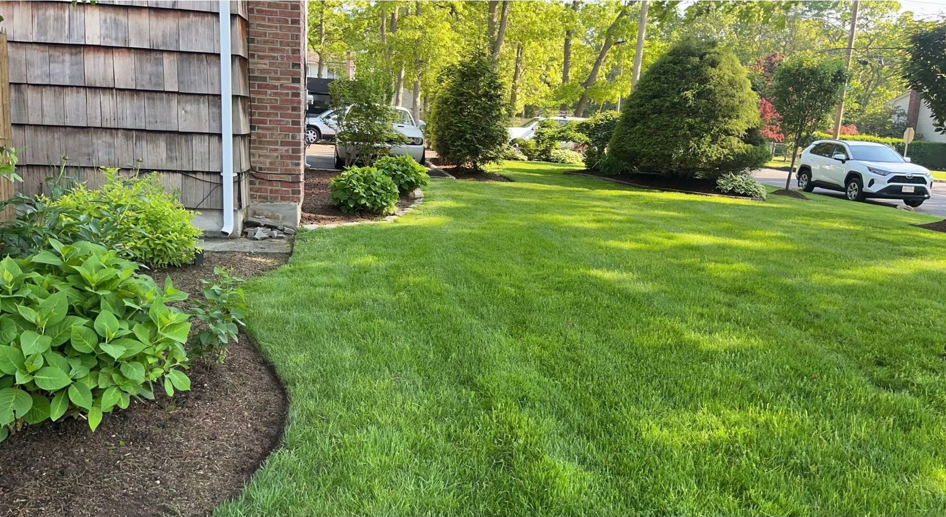 A car is parked in the grass in front of a house.