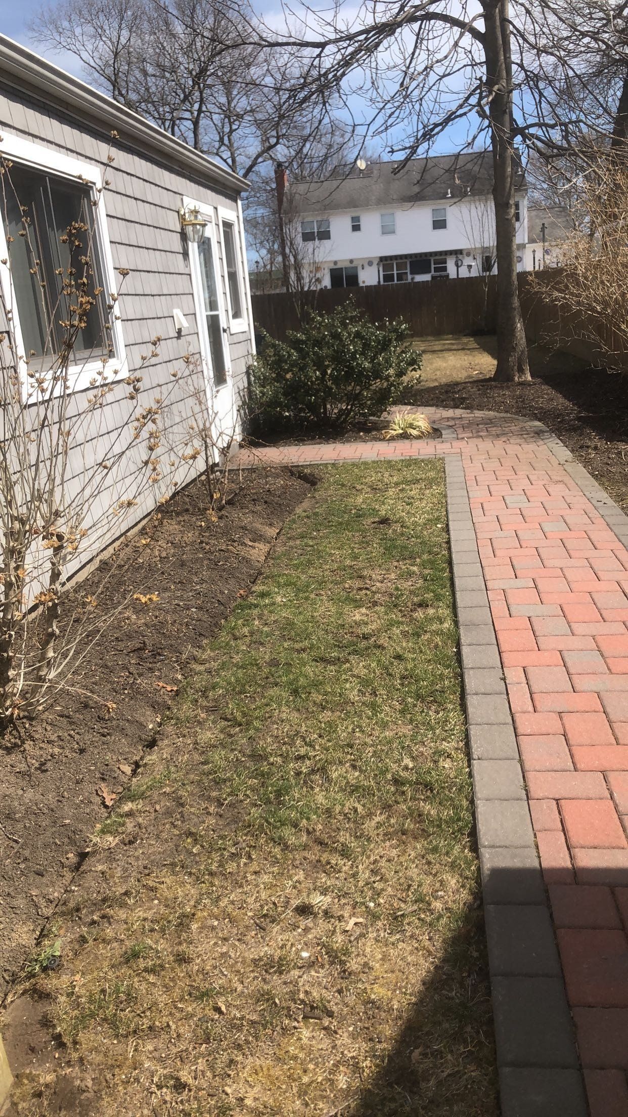 There is a brick walkway leading to a house.