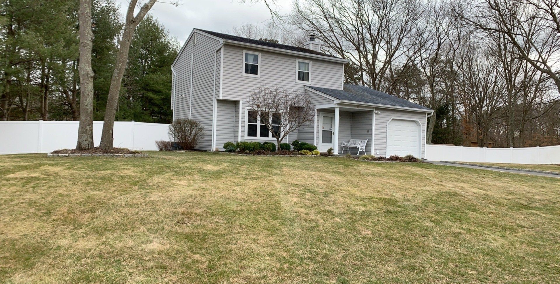 A house with a large lawn in front of it and a white fence.