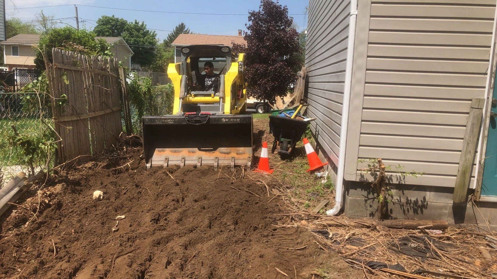 A bulldozer is moving dirt in front of a house.