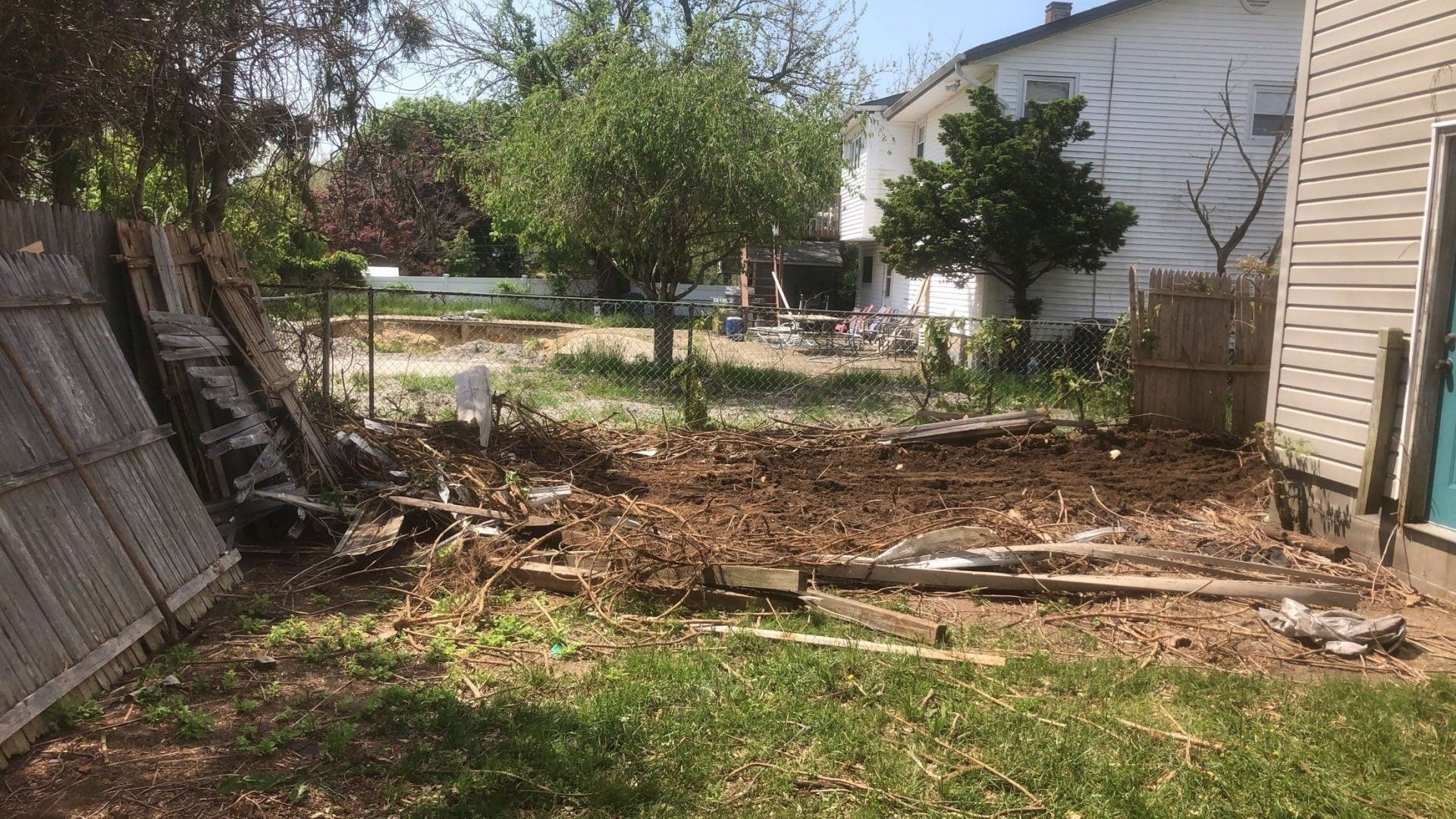 A backyard with a fence and a house in the background.