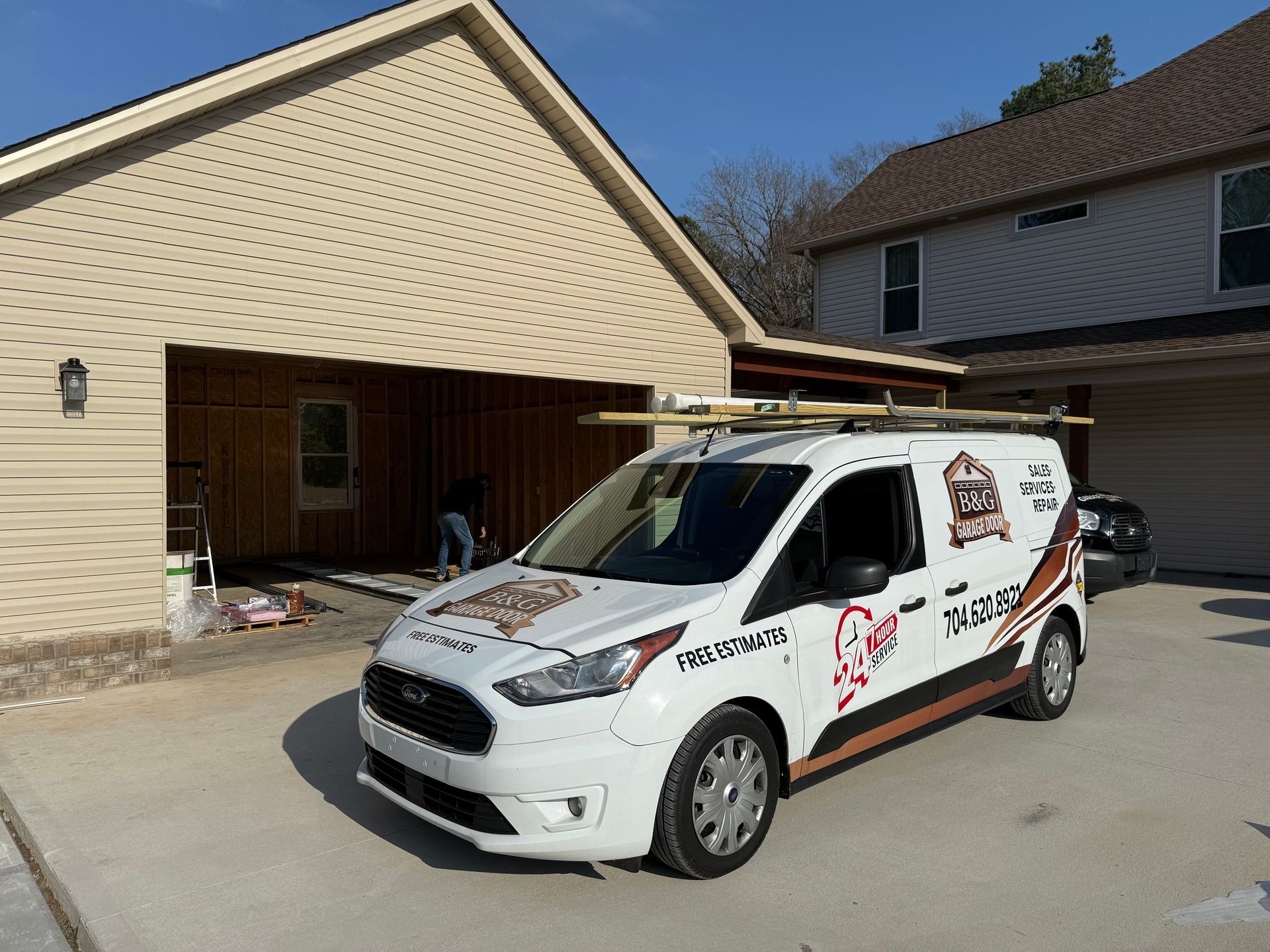 White service van parked in a driveway beside a beige garage under a clear blue sky