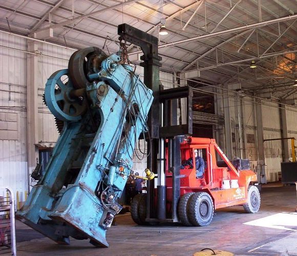 A red crane is lifting a machine into the air.