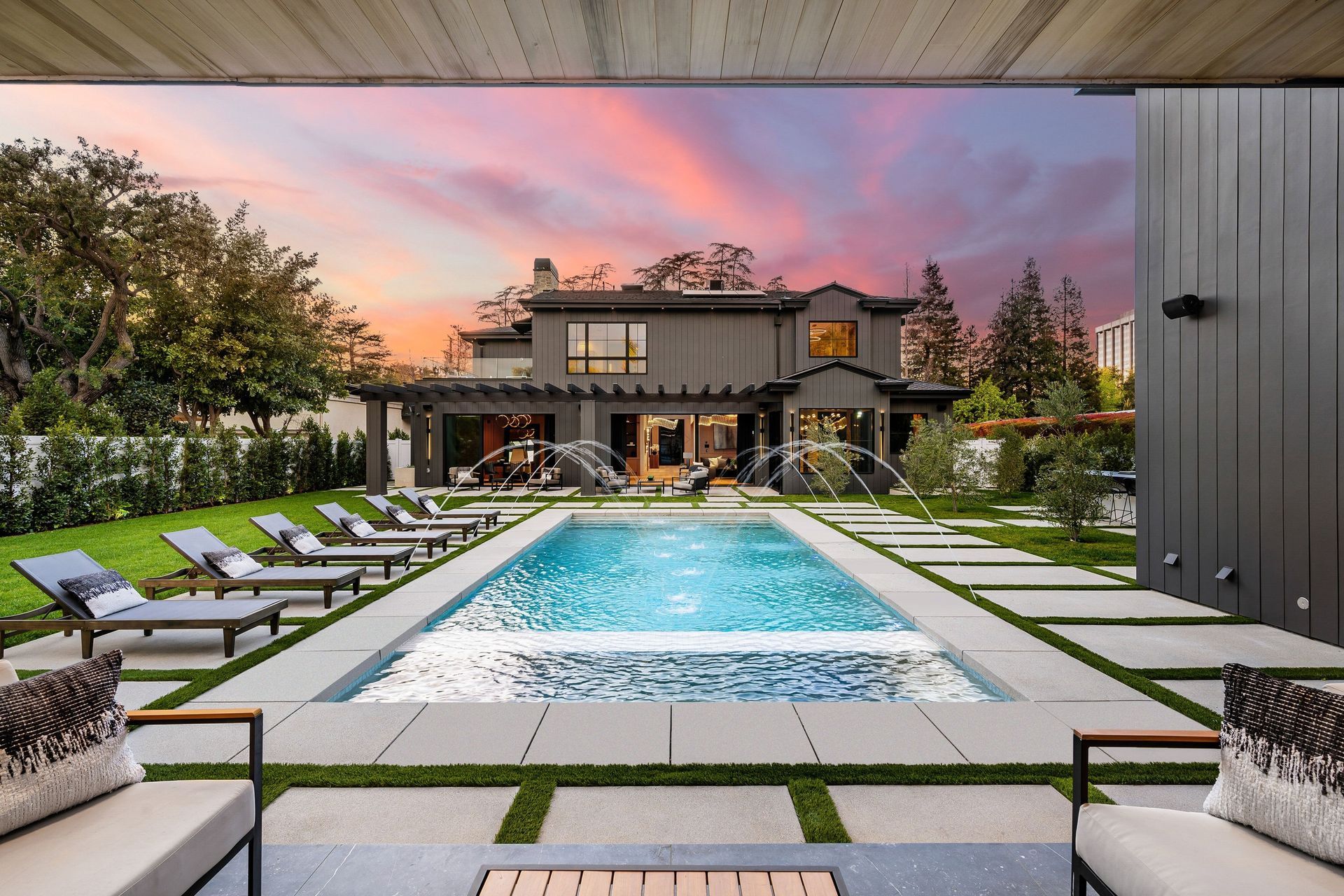 Luxury home with pool, lounge chairs, and vibrant sunset.