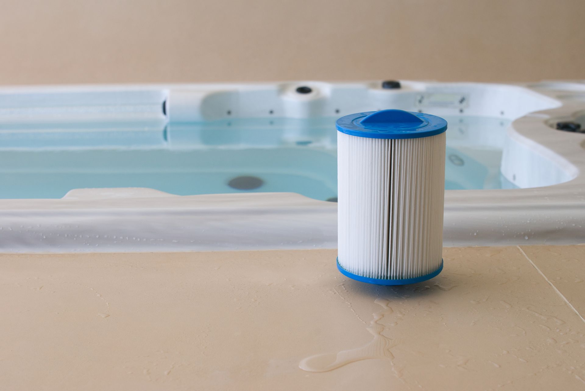 Spa filter leaning next to a spa filled with blue water.