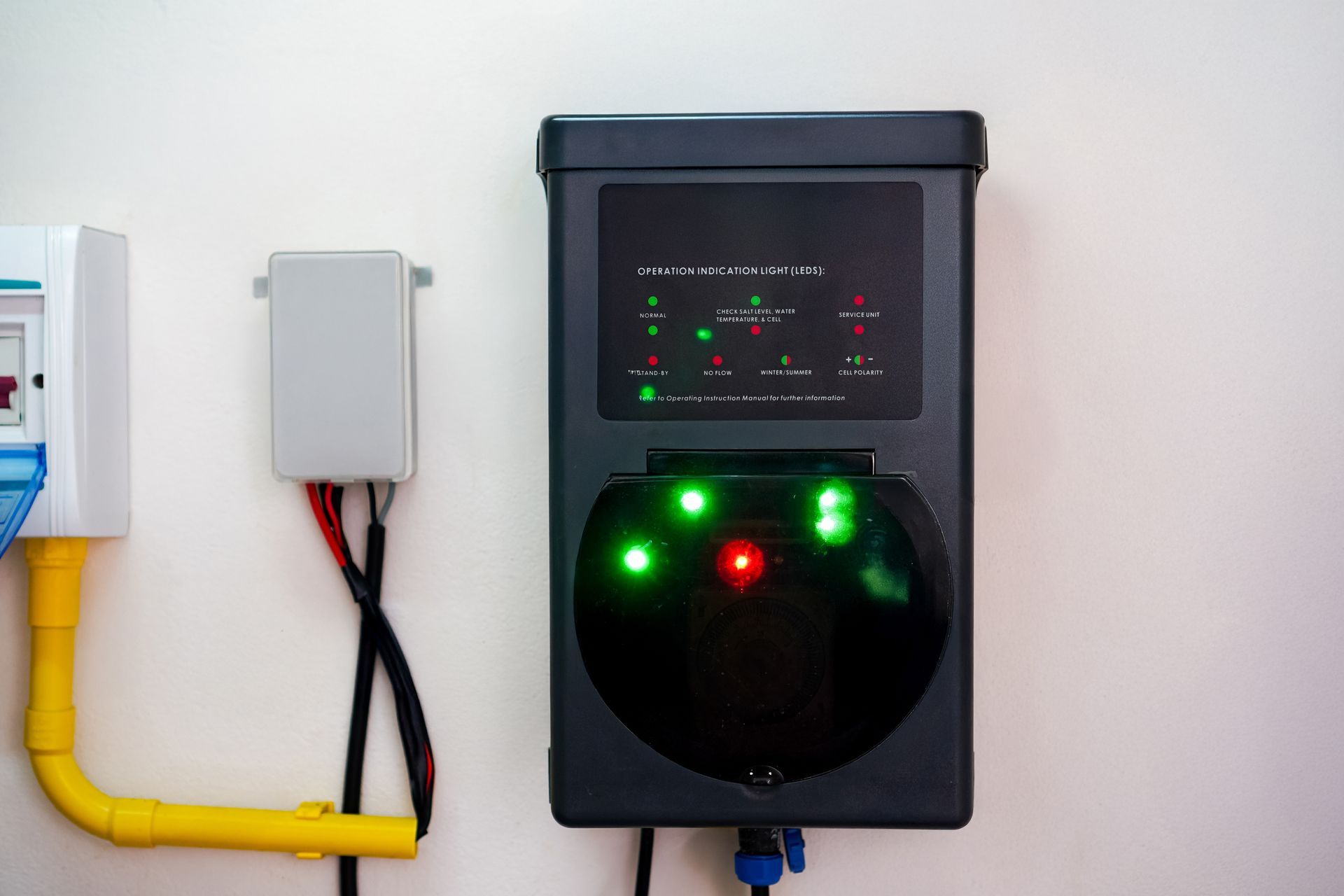 Electric vehicle charger mounted on a white wall with green and red indicator lights.